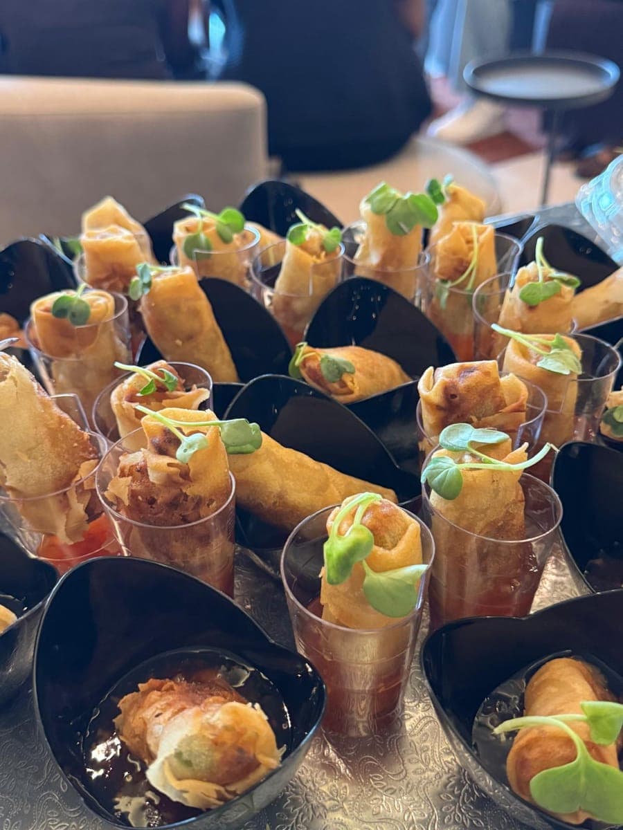 Spring rolls served upright in cups, garnished with microgreens