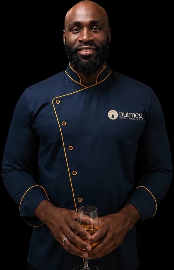 Chef Fred in a navy Nutmeg chef's jacket, holding a glass